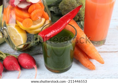 Jar of cut vegetables and glass of fresh vegetable juice with vegetables on wooden background