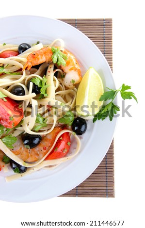 Fresh prawns with spaghetti, olives, tomatoes and parsley in a big round plate on a napkin on white background isolated