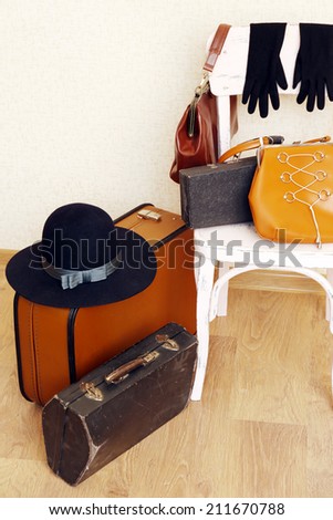 Vintage old travel suitcases on floor and chair with female things