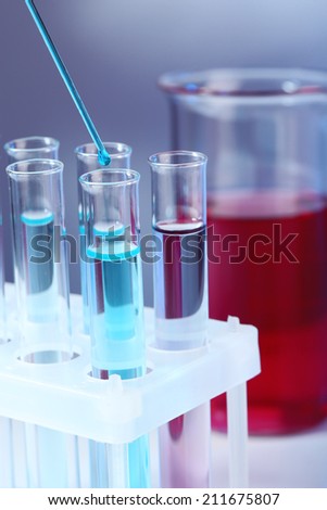 Test tubes with blue liquid and glass with red liquid on light background