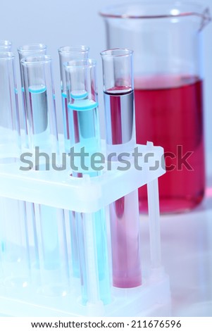 Test tubes with blue liquid and glass with red liquid on light background