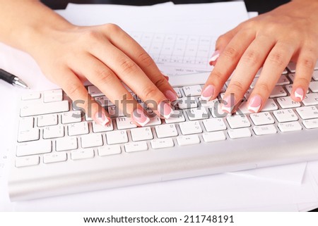 Female hands typing on keyboard, close-up, on light background