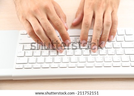 Man working with keyboard on wooden table on folders background closeup