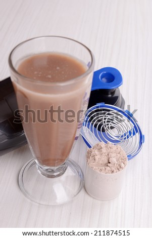Whey protein powder with shake and plastic shaker on wooden background