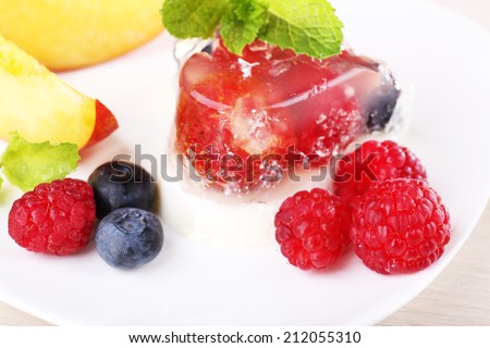 Strawberry jelly cake with fruits and berries on plate on wooden background