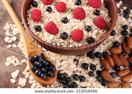 Big brown bowl with oatmeal and berries on a wooden table