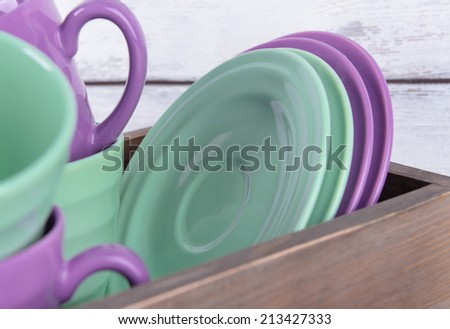 Bright dishes in crate on wooden background