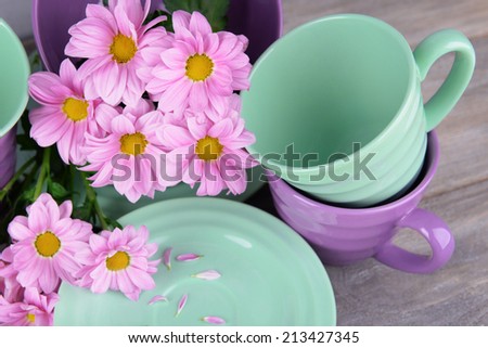 Bright dishes with flowers on wooden background