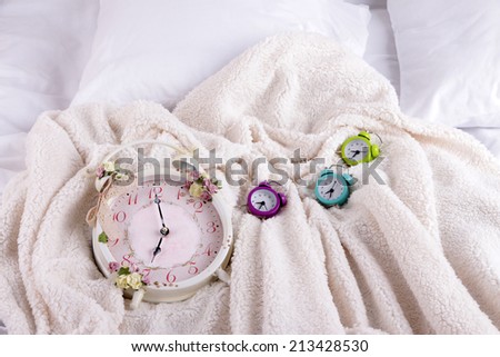 Metal clocks on pillows on a big white bed