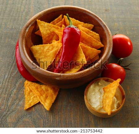 Tasty nachos, red tomatoes and chili pepper in color bowl on wooden background