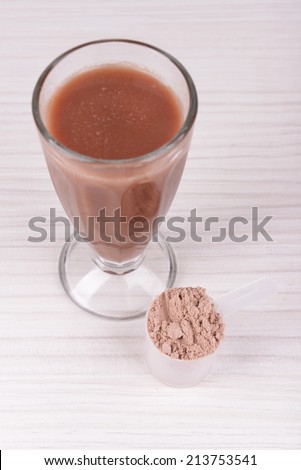 Whey protein powder and chocolate protein shake on wooden background