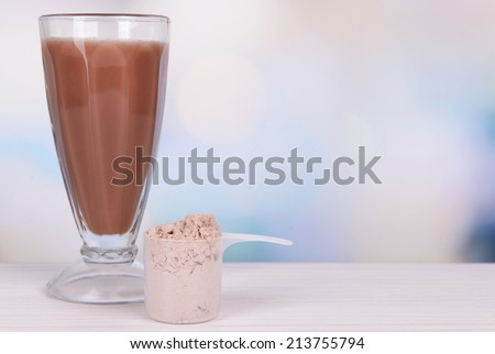 Whey protein powder and chocolate protein shake on table on bright background
