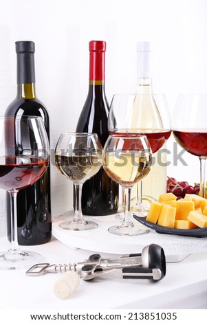 Bottles and glasses of wine, cheese and ripe grapes on table in room