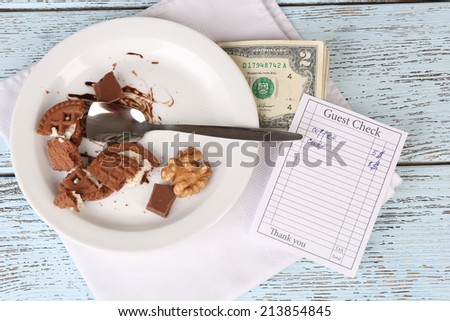 Check, money and remnants of food on table close-up