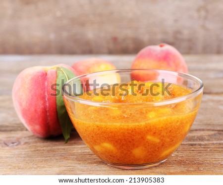 tasty peach jam with fresh peaches on wooden table