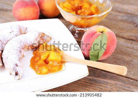 tasty peach jam with fresh peaches and croissants on wooden table