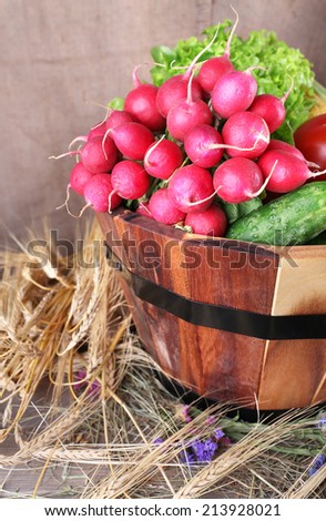 Big round wooden basket with vegetables on sacking background
