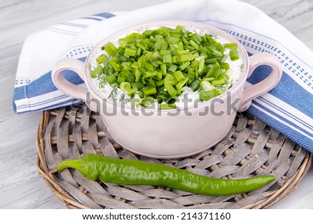 Pink round pan of cream with onion on a round wooden stand and soft napkin on wooden background
