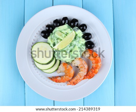 Fresh prawns with avocado, olives, salad and lime on blue wooden background