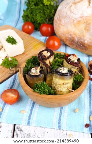 Fried aubergine in a bowl with cottage cheese, bread and parsley on wooden background