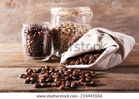 Coffee beans in fabric bag and glass jars on wooden table on wooden background