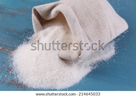 Sugar in bag on color wooden background