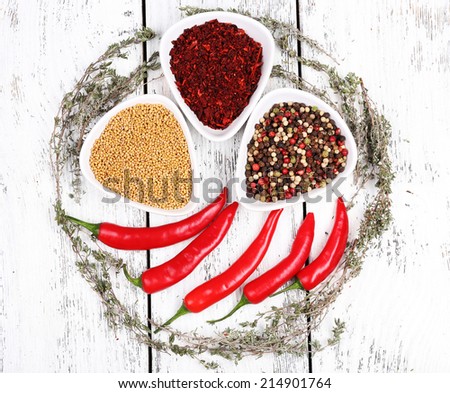Spices in glass round bowls with herbs and chilly pepper on wooden background