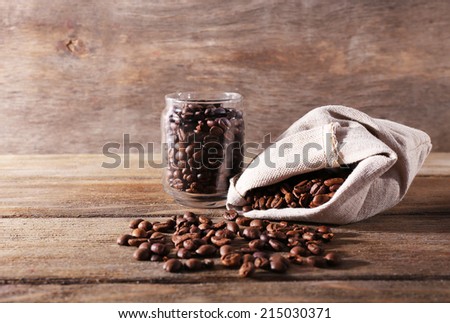 Coffee beans in fabric bag and glass jar on wooden background