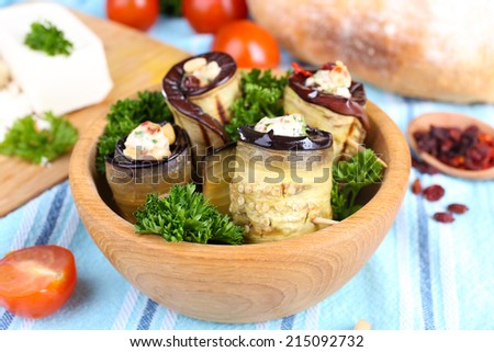 Fried aubergine in a bowl with cottage cheese, bread and parsley on wooden background