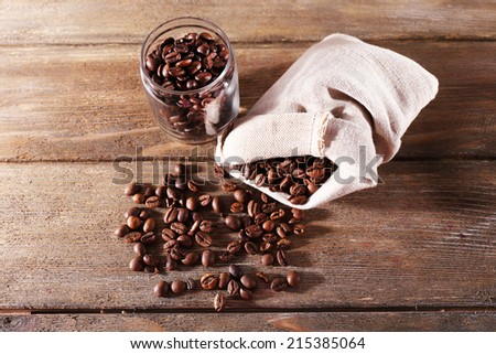 Coffee beans in fabric bag and glass jar on wooden background