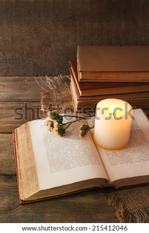 Books, flowers and candle on napkin on wooden table on wooden wall background