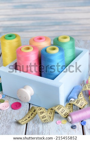 Sewing Accessories in wooden box on table on light blue background