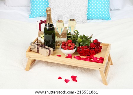Romantic still life with champagne, strawberry and roses on bed
