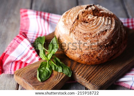 Fresh baked bread and fresh basil on cutting board, on wooden background