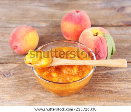 tasty peach jam with fresh peaches on wooden table