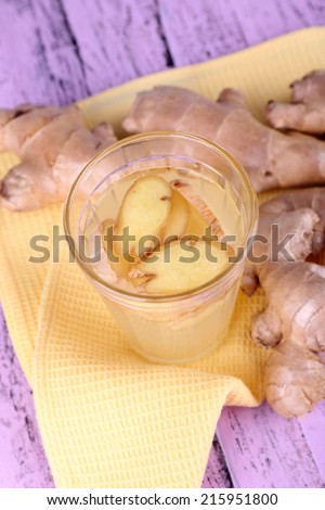 Ginger drink and ginger root on napkin on wooden background