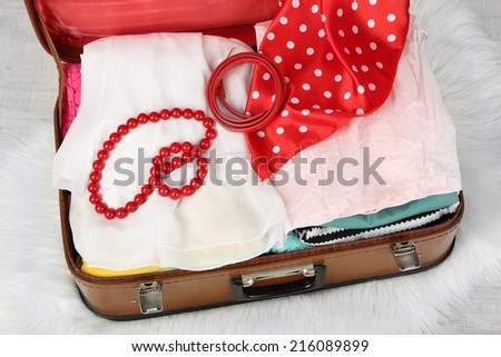 Female clothes in old suitcase on light background