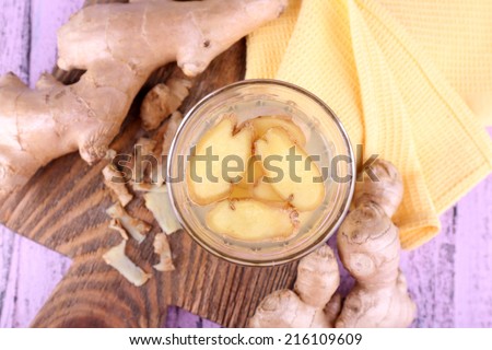 Ginger drink and ginger root and napkin on cutting board on wooden background