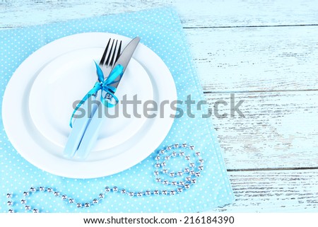 White plates, fork, knife and Christmas decoration on blue polka dot napkin on wooden background