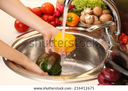 Woman\'s hands washing pepper in sink