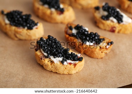 Slices of bread with butter and black caviar on paper background