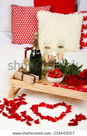 Romantic still life with champagne, strawberry and roses on bed