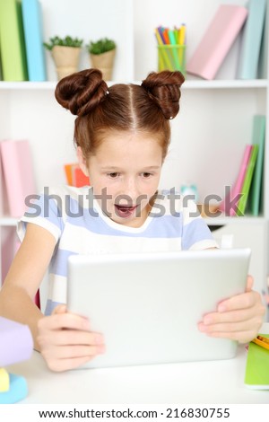 Cute girl with tablet at workplace in classroom