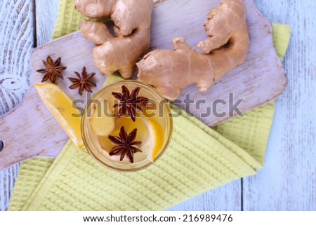 Glass of ginger drink with lemon on napkin on cutting board on wooden background