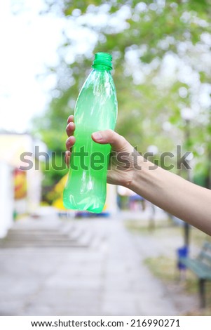 Hand holds bottle with sweet water on bright background