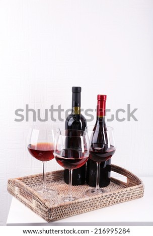 Glasses and wine bottle on tray in room
