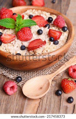 Tasty oatmeal with berries on table close-up