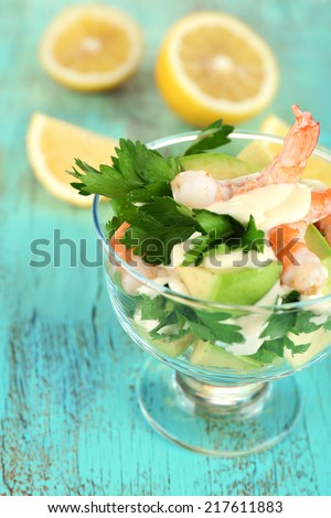Tasty salad with shrimps and avocado, on wooden background