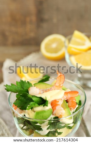 Tasty salad with shrimps and avocado on plate, on wooden background