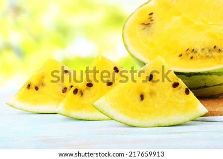 Slices of yellow watermelon on wooden table on natural background